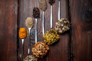 Top view sweets handmade teaspoons with spices for handmade sweets from nuts, dried fruits and honey on a dark wooden background